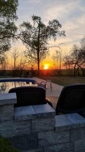 a sunset over a pond with two benches and a car at Black Horse in Pasłęk