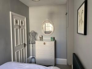 a bedroom with a white dresser and a mirror at Chic Apt in Central Cheltenham in Cheltenham
