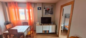 a small room with a television and a table with a tableablish at www apartamentovaldivia es Parking incluido in León