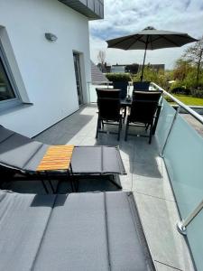 patio con tavolo, sedie e ombrellone di Luv-Moderne Neubauwohnung in Strandnähe-Wallbox a Wremen