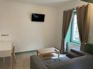 a living room with a couch and a tv on the wall at Le Lion d'Or in La Chaise-Dieu