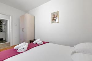 a white bedroom with a large bed with towels on it at Apartment Riva in Makarska