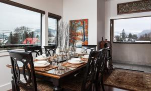 uma sala de jantar com mesa, cadeiras e janelas em Alpenglow Penthouse by Revelstoke Vacations em Revelstoke