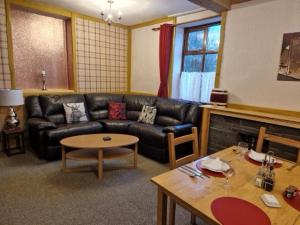 sala de estar con sofá de cuero negro y mesa en Ty Llew, en Llandysilio