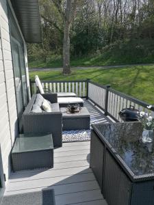 a patio with a couch and a table on a porch at STUNNING, PEACEFUL LODGE on edge of New Forest and 800m from sea ENTERTAINMENT and LEISURE PASSES INCLUDED in Milford on Sea
