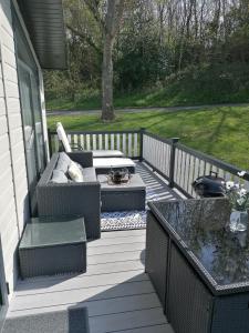 a patio with a couch and a table on a porch at LUXURY LODGE on edge of New Forest and 800m from sea ENTERTAINMENT and LEISURE PASSES INCLUDED in Milford on Sea