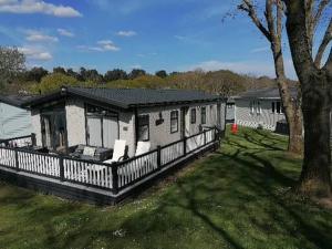 a house with a fence next to a yard at STUNNING, PEACEFUL LODGE on edge of New Forest and 800m from sea ENTERTAINMENT and LEISURE PASSES INCLUDED in Milford on Sea