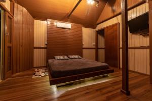1 dormitorio con 1 cama en una habitación con paredes de madera en @Chalet.Home, en Nova Veneza