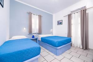 a bedroom with two beds with blue sheets at Fortuna Perissa in Perissa
