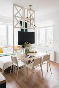 a white dining room with a white table and chairs at Lux Apartment II in Gdańsk