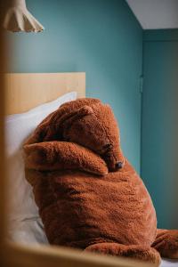 a brown teddy bear sitting on top of a bed at Hotel Spa Azteca Barcelonnette in Barcelonnette
