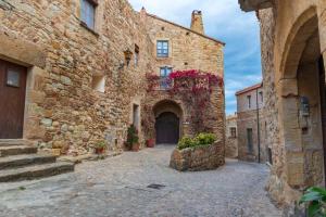 un callejón en un antiguo edificio de piedra con flores en Can Costals Terraza, en Pals