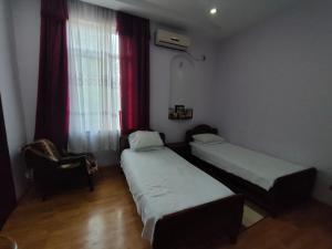 um quarto com duas camas e uma cadeira e uma janela em Guest House Nadejda em Batumi