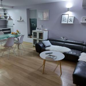 a living room with a black leather couch and a table at Ivančica in Aljmaš