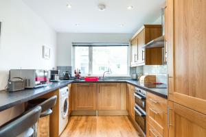 a large kitchen with wooden cabinets and a window at Orchard View in St Austell
