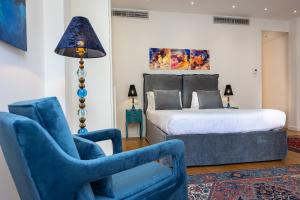 a bedroom with a bed and two blue chairs at Suite della Pigna in Rome