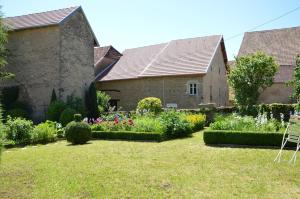 uma casa antiga com um jardim em frente em La ferme aux glycines em Aillevans