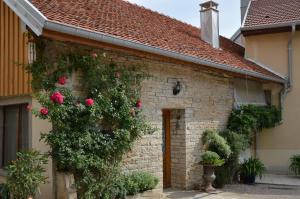 a brick house with roses on the side of it at La ferme aux glycines in Aillevans