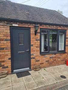 a brick house with a black door and a window at ROYAL OAK in Kinnersley