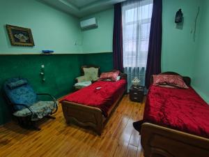 um quarto com 2 camas, uma cadeira e uma janela em Guest House Nadejda em Batumi