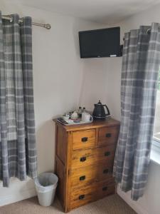 a bedroom with a wooden dresser with a television on the wall at ROYAL OAK in Kinnersley