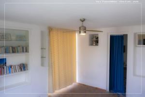 a room with a ceiling fan and blue curtains at Il Leone Di Mare in Procida