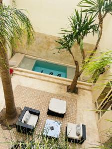 a swimming pool with two chairs and a table and two palm trees at Riad 144 in Marrakech