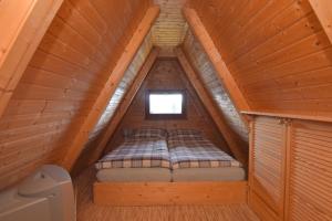 a bed in the attic of a wooden cabin at Finnhütte im Herzen des Thüringer Wald/ Haus Alwin in Heidersbach