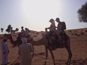 a group of people riding on a camel in the desert at Bedouin Oasis Desert Camp- Ras Al Khaimah in Ras al Khaimah