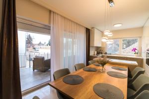 a dining room with a wooden table and a kitchen at Thermal Lux Weninger Apartman in Kiskunhalas