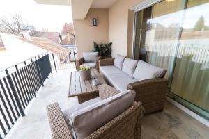 een patio met banken en een tafel op een balkon bij Thermal Lux Weninger Apartman in Kiskunhalas