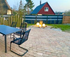 Un patio con mesa y sillas y una fogata. en Ferienwohnung Born am Darßwald EG, en Born