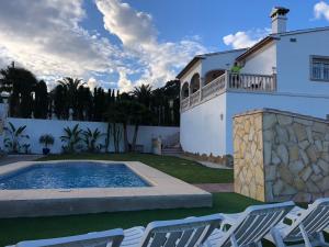 una casa con piscina y 2 sillas de césped en Villa Maja, en Calpe