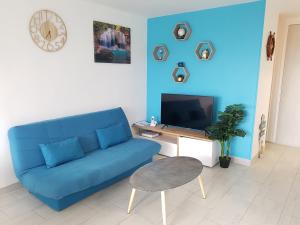 een woonkamer met een blauwe bank en een tv bij 2/3 Pièces - Balcon Vue Mer - Parking in Trouville-sur-Mer