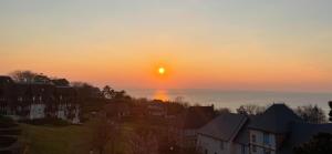 een zonsondergang boven een stad met huizen en de oceaan bij 2/3 Pièces - Balcon Vue Mer - Parking in Trouville-sur-Mer