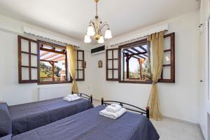 two beds in a bedroom with windows and a chandelier at VILLA KONSTANTINA Sidari in (( Sgoúrna )) +33 photos