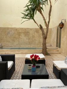 a room with a palm tree and a table with flowers at Riad 144 in Marrakech