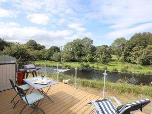 a deck with a table and chairs and a river at Llety'r Bugail 1 in Caernarfon