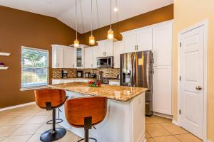 a kitchen with white cabinets and a counter with two bar stools at Happy Home in Perdido Key