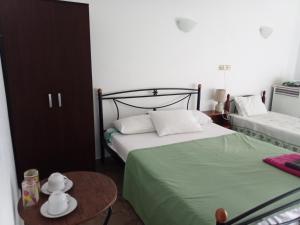 una camera con 2 letti e un tavolo con un tavolino sidx sidx. di Nikos Rooms a Loutra Edipsou