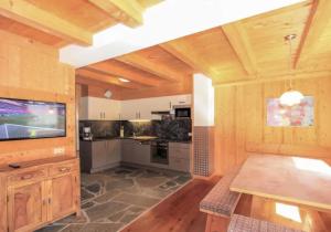 a large kitchen with wooden walls and a flat screen tv at Alois & Elisabeth, Chalet in Tux