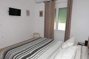 sypialnia z łóżkiem, telewizorem i oknem w obiekcie Ηermes Apartment - 3 w Nauplionie