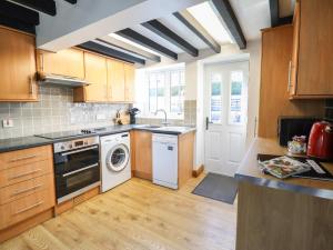 a kitchen with wooden cabinets and a white dishwasher at Tan Y Capel in Llanbrynmair