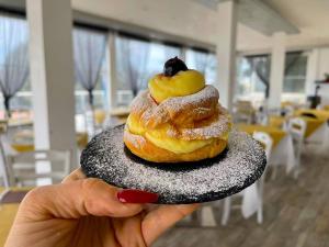 a person holding a stack of donuts on a plate at Frontemare Hotel Village & Ristorante in Rodi Garganico