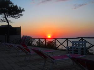 a group of lawn chairs sitting in front of a sunset at Frontemare Hotel Village & Ristorante in Rodi Garganico