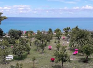 a park with pink chairs and trees and the ocean at Frontemare Hotel Village & Ristorante in Rodi Garganico