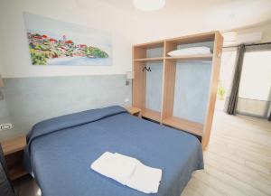 a bedroom with a blue bed with two towels on it at Frontemare Hotel Village & Ristorante in Rodi Garganico