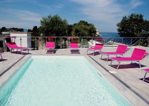 a swimming pool with pink chairs and a swimming pool at Frontemare Hotel Village & Ristorante in Rodi Garganico