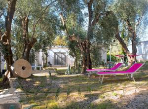 a yard with two pink chairs and trees at Frontemare Hotel Village & Ristorante in Rodi Garganico