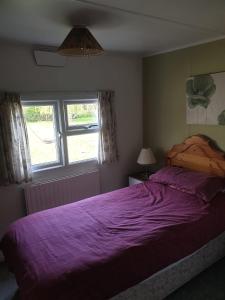 a bedroom with a purple bed and a window at The Homestead, Cliff-en-Howe Rd, Pott Row, Kings Lynn in Grimston